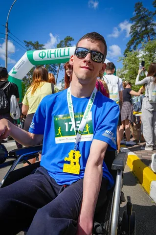 Учасник забігу в синій футболці з медаллю на фінішу