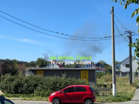 Червоний автомобіль біля будівлі з димом
