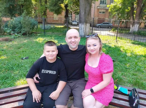 Чоловік та двоє дітей сидять на лавці в парку