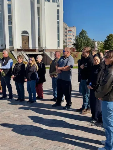 Група людей стоїть на площі біля будівлі