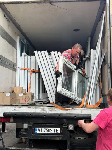 Чоловік розвантажує вікна з вантажівки