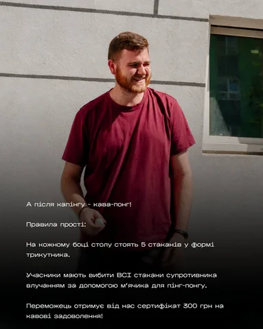 Чоловік у бордовій футболці біля стіни будівлі
