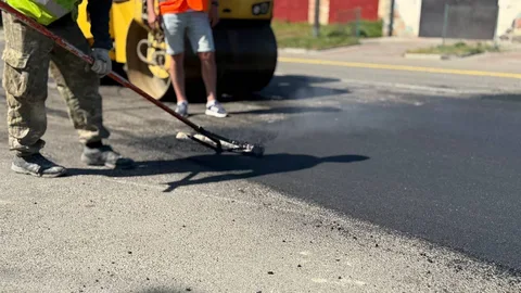 Робітник розрівнює асфальт під час ремонту дороги