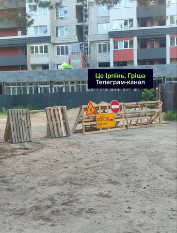 Перекриття дороги дерев'яними бар'єрами та знаками біля будівель