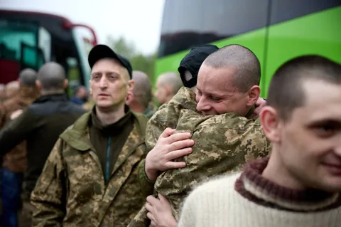 Військові в камуфляжі обіймаються біля автобуса