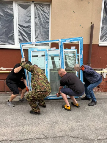 Люди встановлюють нове вікно в пошкоджену будівлю