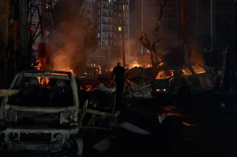 Нічна вулиця міста з палаючими автомобілями та димом