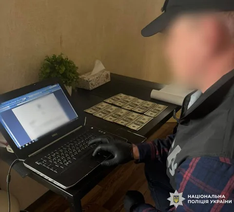Людина за столом з ноутбуком та грошима