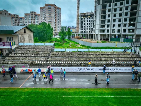 Люди на вулиці біля білого банера з написом