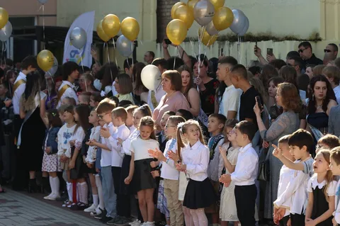 Учні в білих сорочках з золотими та сірими кульками на святі