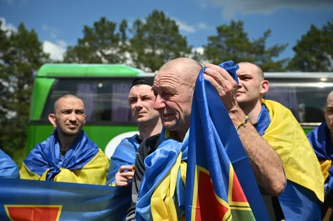 Група чоловіків з українськими прапорами біля автобуса