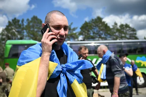 Чоловік у жовто-блакитній стрічці розмовляє по телефону