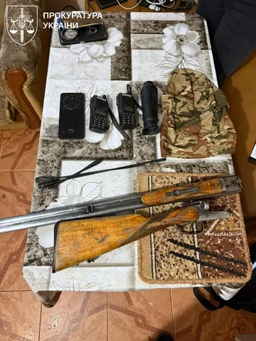Вилучена зброя, телефони та військовий одяг на столі