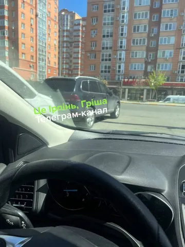 Вид з салону автомобіля на припаркований автомобіль біля багатоповерхових будинків