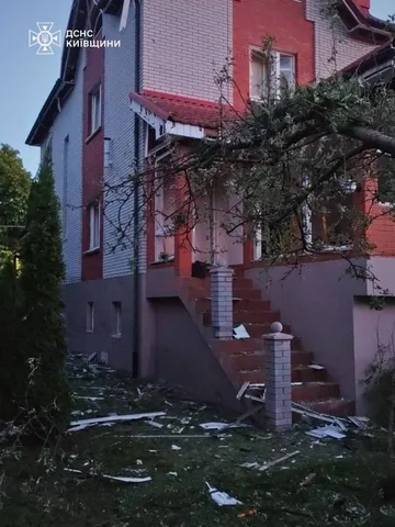 Пошкоджена будівля з вибоїнами на фасаді та подвір'ї