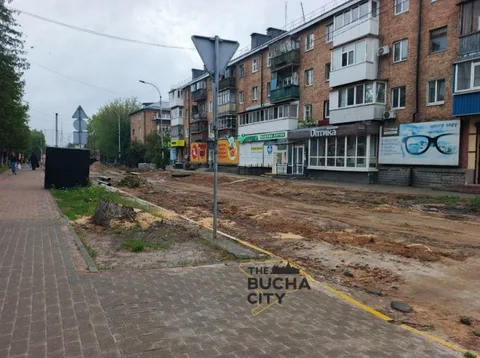 Розкопана вулиця з пошкодженим асфальтом і будівлями