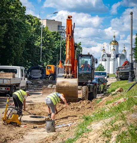 Будівельні роботи на вулиці з екскаватором і робітниками