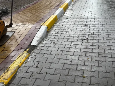 Пошкоджена бруківка на тротуарі з жовтою розміткою