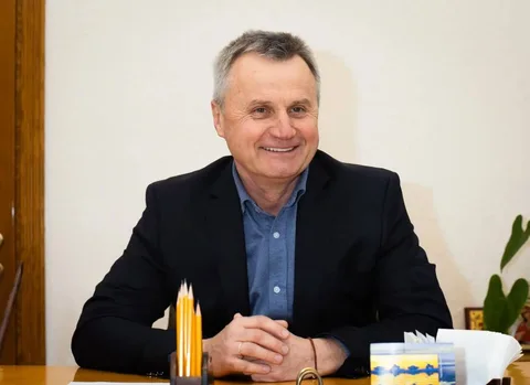Чоловік середнього віку в чорному піджаку за столом