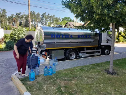 Людина наповнює пластикові каністри водою з цистерни на вулиці